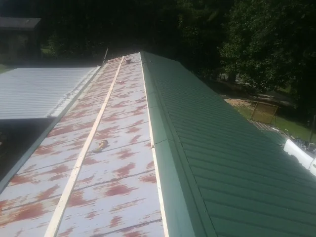 Old rusted panels beside newly installed green metal roofing — Wind Damage Roof Repair by Roofing Brothers in Macedon