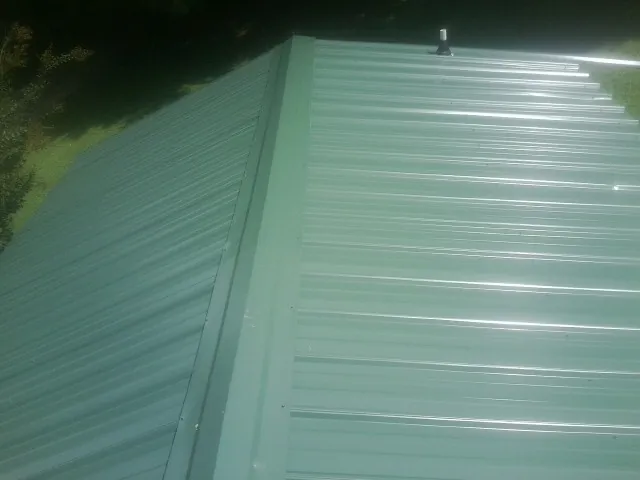 New green metal panels meeting at the ridge of a roof — Flat Roof Repair work by our crew in Macedon
