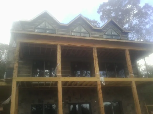 Dormers and porch framing on a large log home under construction — Roof Coating work by our crew in Macedon