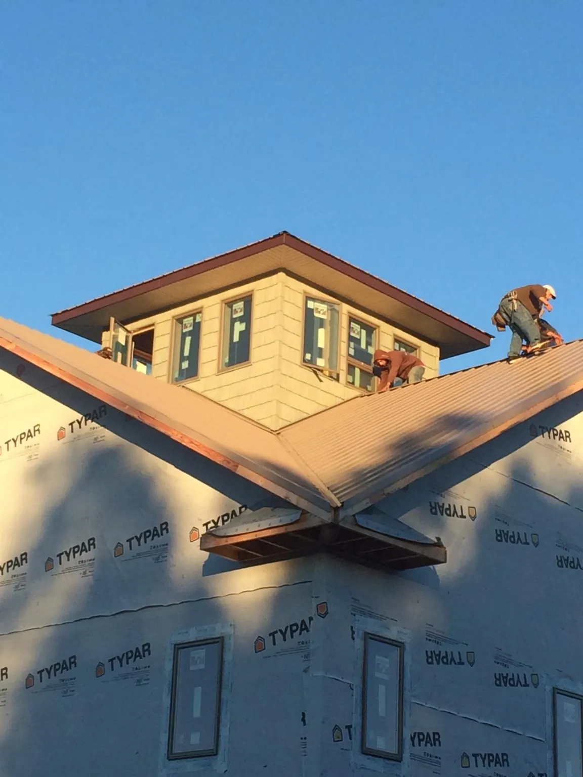 Roofers working around a rooftop cupola on a new metal roof at sunset — Roof Waterproofing in Macedon by Roofing Brothers